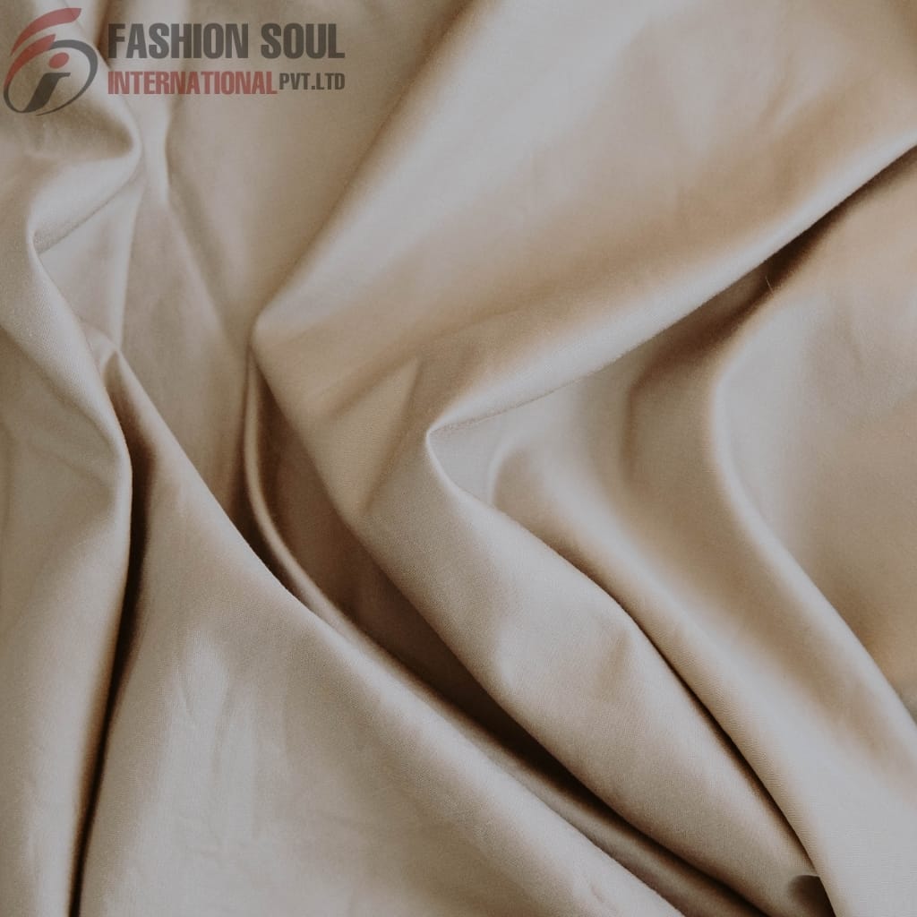 Close-up of beige satin fabric with elegant folds and drapes, showing its smooth and shiny texture.