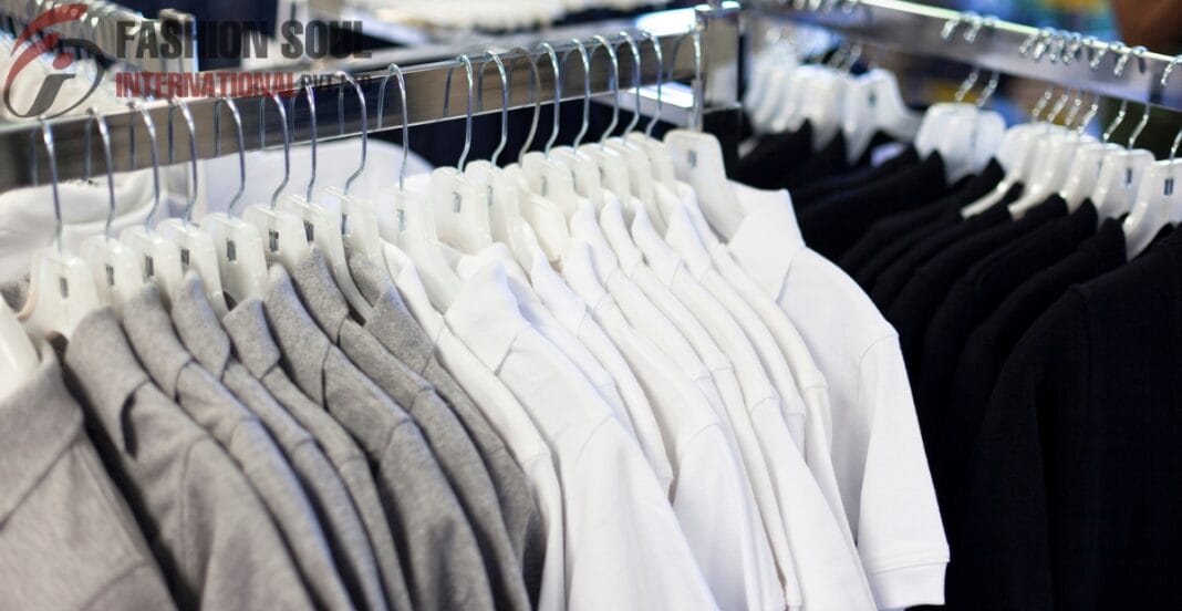 Rows of neatly arranged gray, white, and black polo shirts hanging on white hangers on a metal clothing rack at an outdoor market or store.