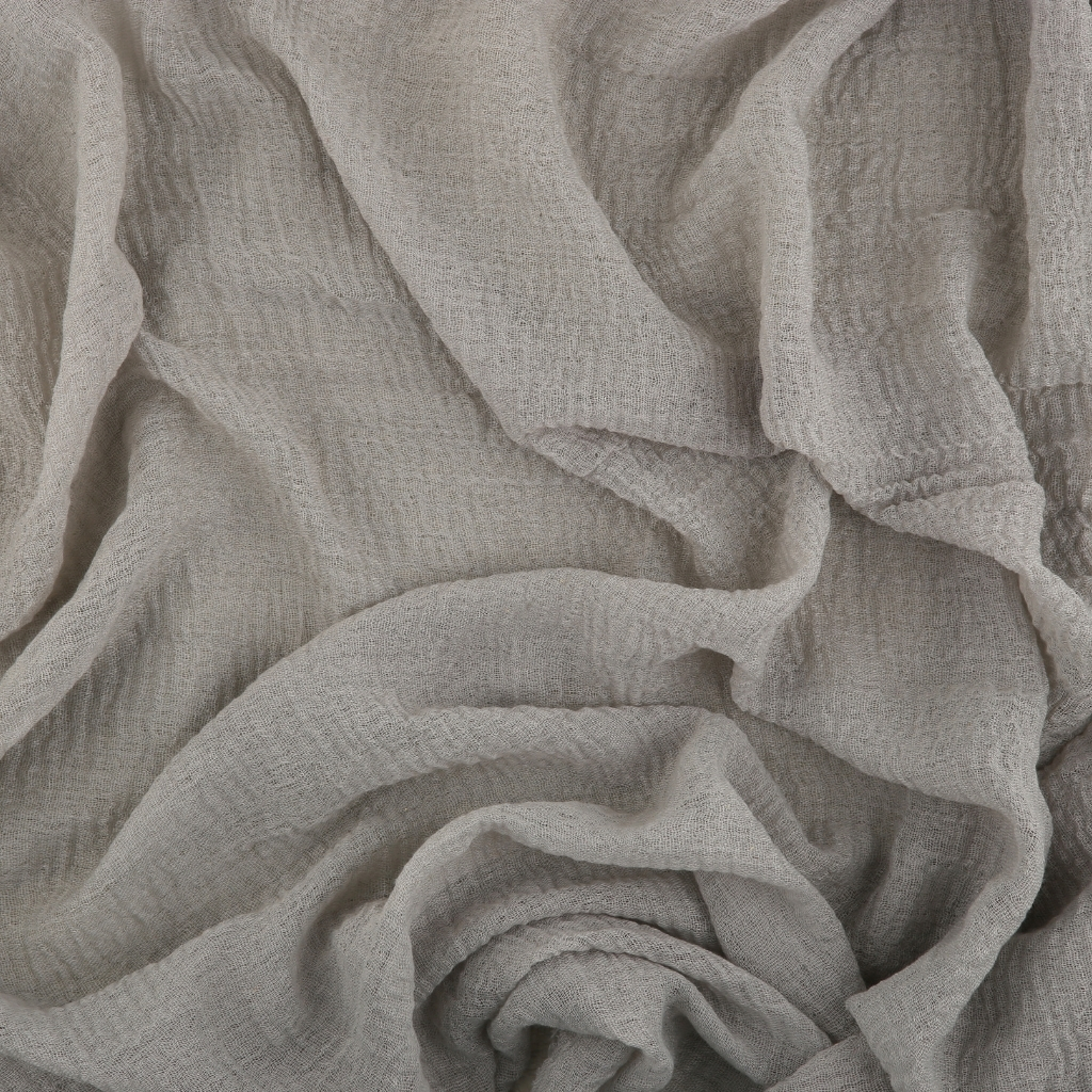 Close-up of light-colored, textured fabric with soft, flowing folds and creases.