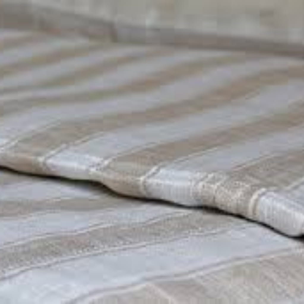 Close-up of a soft, beige and gray striped fabric surface, likely a bedspread or blanket.