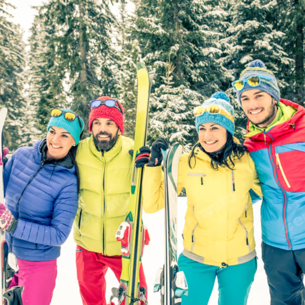A group of five friends dressed in vibrant, eco-friendly winter sportswear, smiling and standing close together in a snowy forest, ready for skiing.