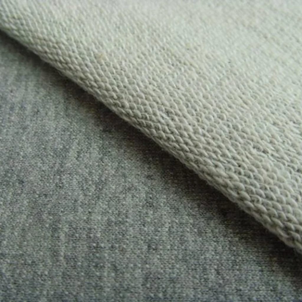 Close-up of a textured beige fabric laid over a rough gray surface.