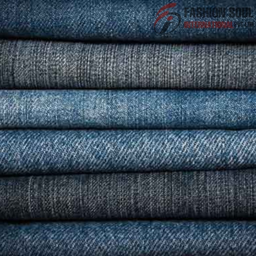 Stack of folded denim fabrics in varying shades of blue and gray, with a visible watermark in the top right corner.