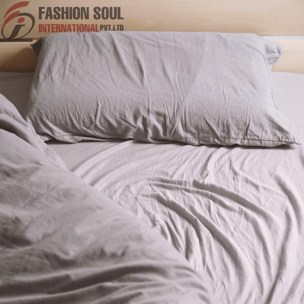 Close-up of a soft, light gray bed sheet bundle with pillow on a cozy, made bed.