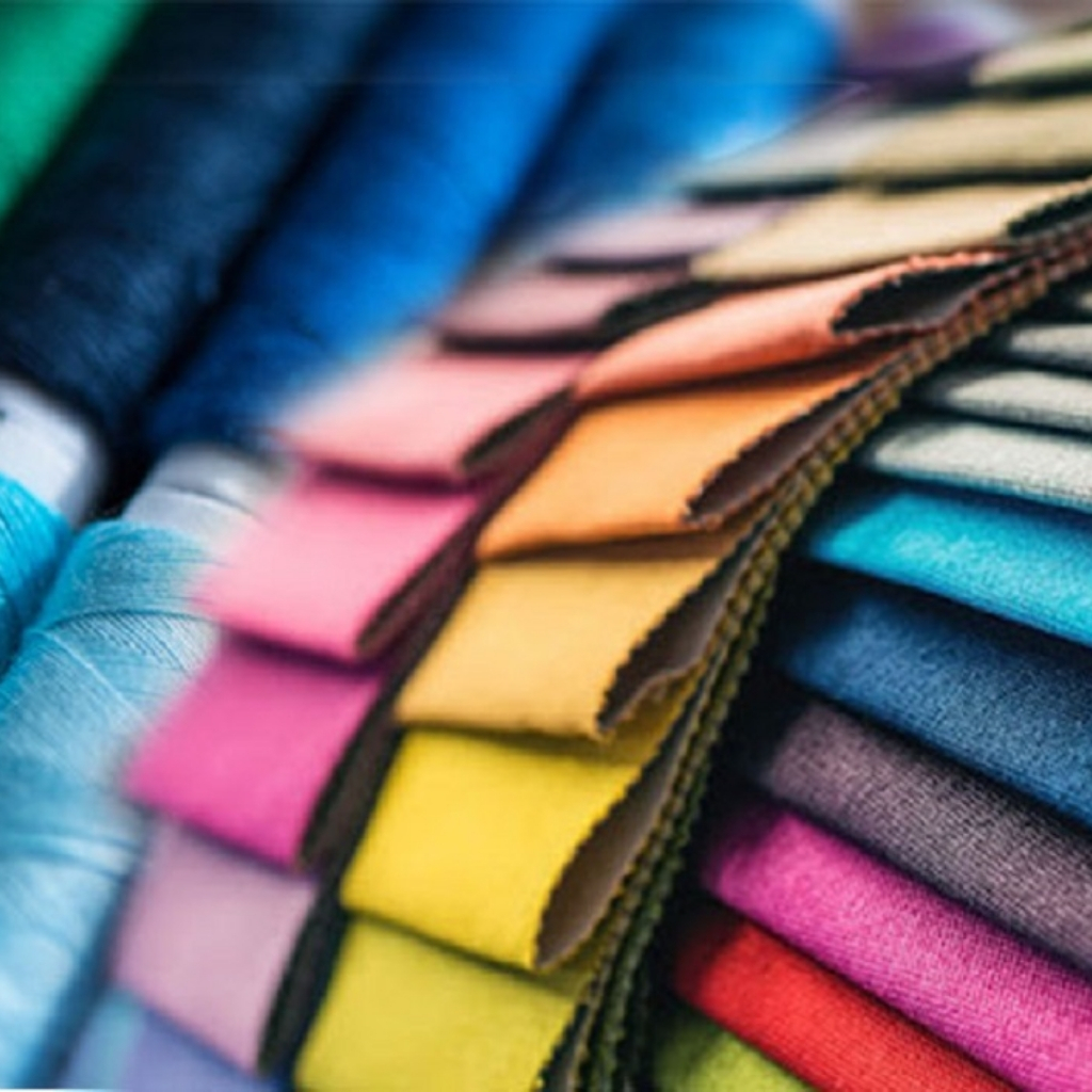 A colorful display of fabric swatches arranged in a curved stack, featuring various vibrant colors including blue, pink, yellow, orange, green, and purple.