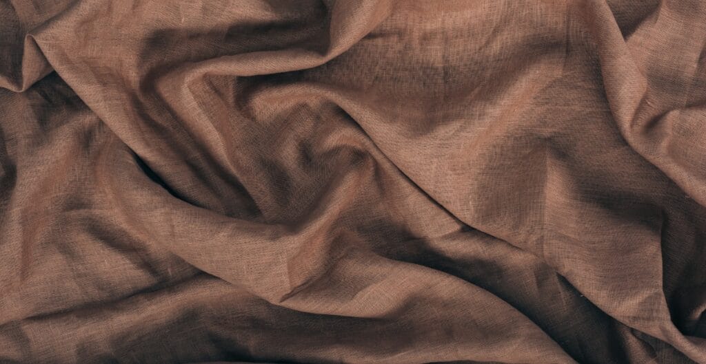 A close-up of brown, crumpled fabric with a slightly sheer texture.