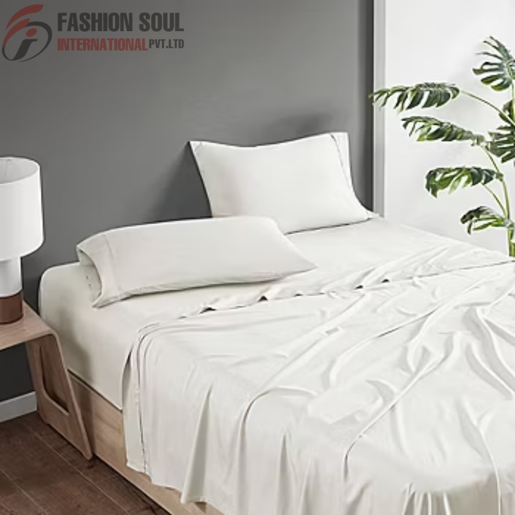 A modern bedroom with a neatly made bed in white bedding, a wooden side table with a white lamp, a gray wall, and a large green plant near a window.