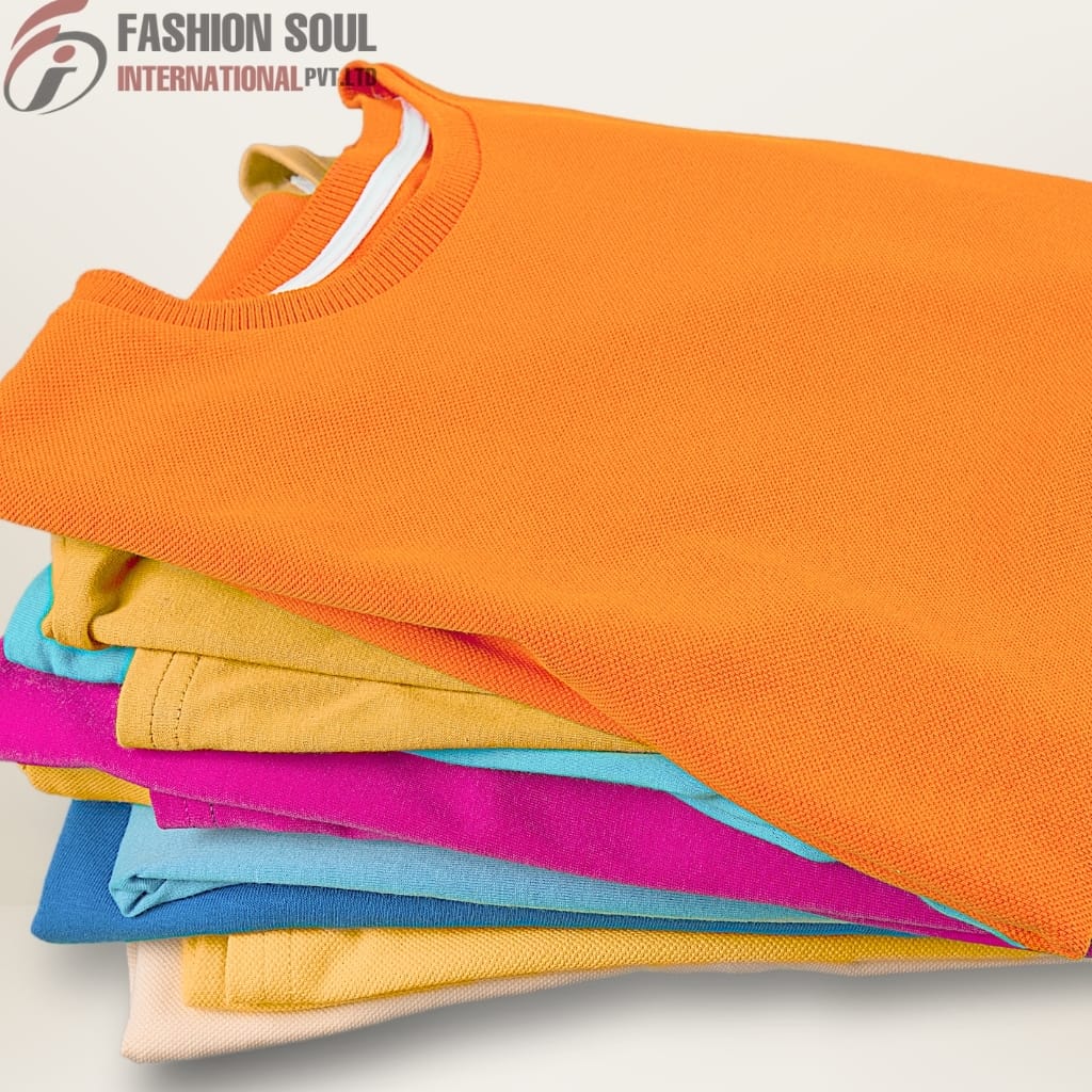 Stacked colorful sweatshirts or t-shirts in shades of orange, yellow, pink, blue, and beige, folded neatly.