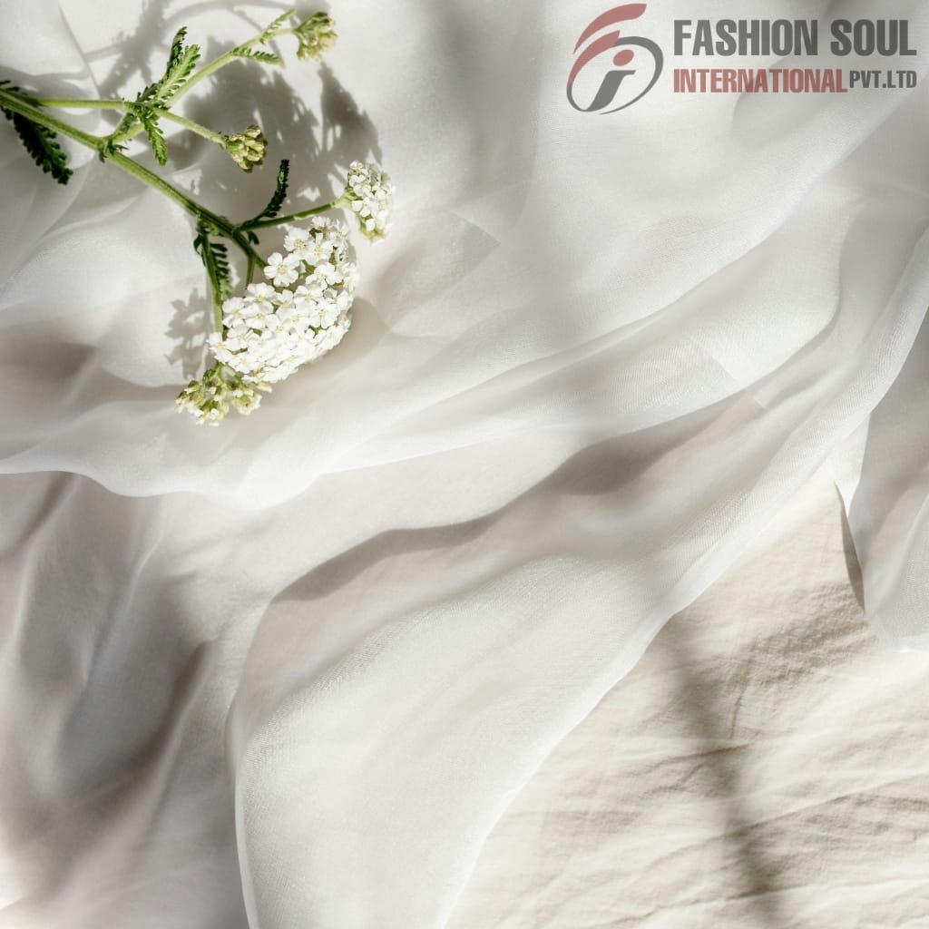 Light, flowing white fabric with a small branch of white flowers resting on it, and the "Fashion Soul International Pvt. Ltd." logo in the upper right corner.