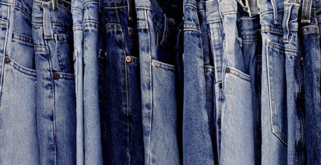"Close-up of a pair of jeans and fabric swatches showing different indigo hues and textures, representing denim as a driver of trends."