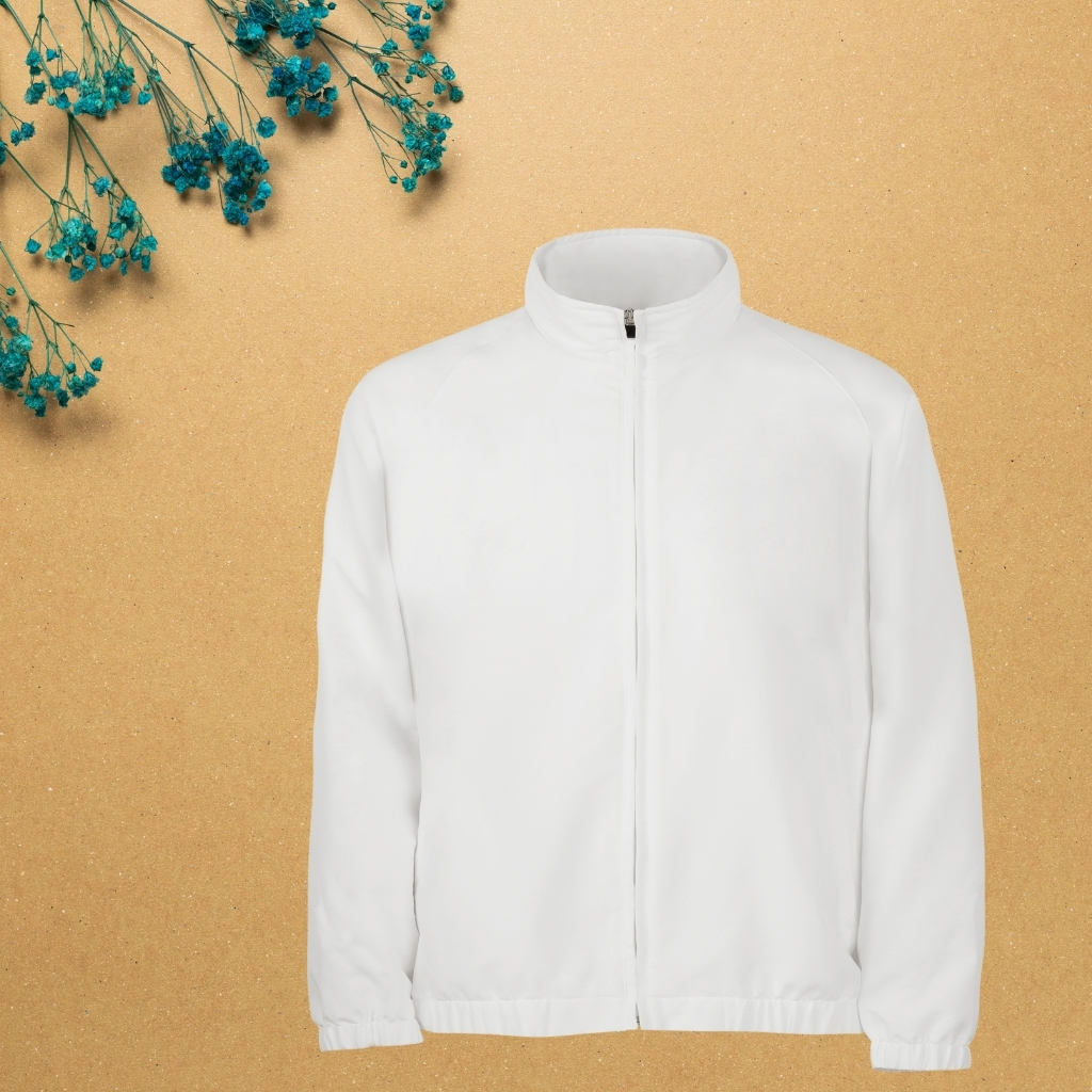 A plain white sports jacket with a zipper, displayed on a background of beige textured surface with blue dried flowers in the top left corner.