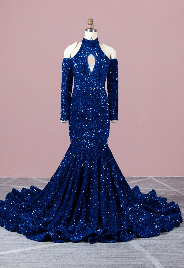 A stunning, royal blue sequin ball gown with a mermaid silhouette, long sleeves with cutouts, and a high neckline featuring a keyhole detail, displayed on a mannequin against a pink wall.