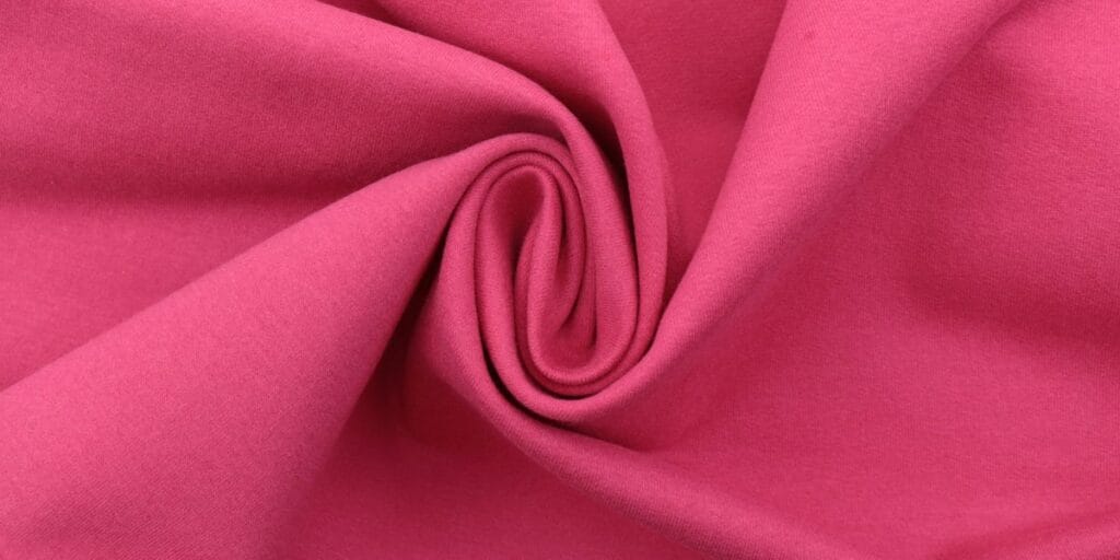 Close-up of a swirl of pink stretchy fabric with a soft and smooth texture.