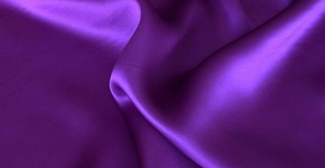 Close-up of smooth, purple satin fabric with soft folds and a lustrous sheen.