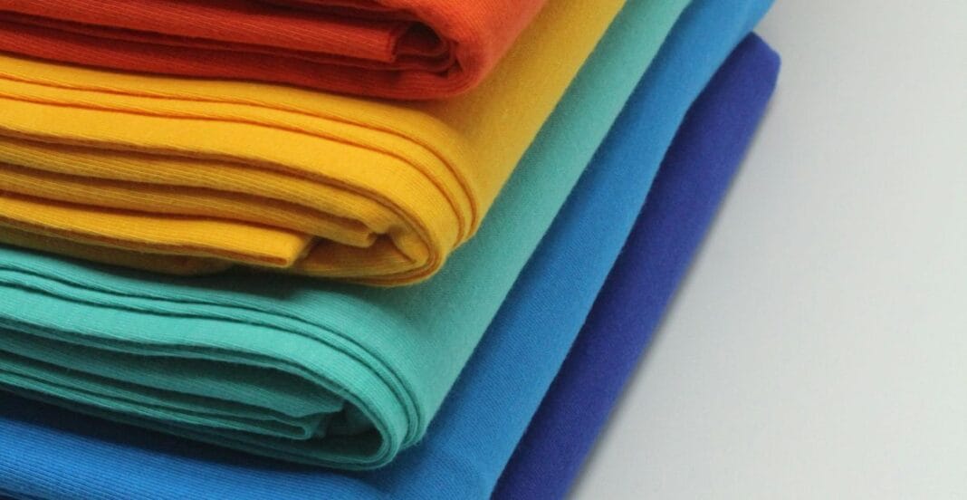 Stack of neatly folded colorful fabrics in red, yellow, turquoise, and shades of blue.