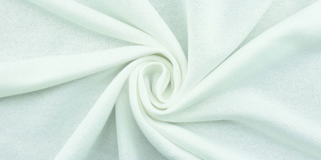 Close-up of a light mint green fabric with a soft texture, swirled into a circular fold.