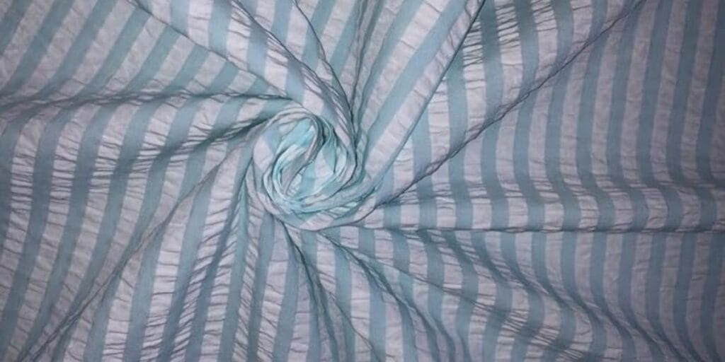 Close-up of light blue and white striped fabric twisted into a swirl pattern.