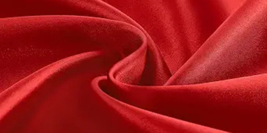 Close-up of red satin fabric with soft folds and a smooth, shiny surface.