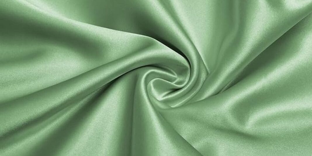Light green satin fabric with a smooth, shiny surface twisted into a swirl pattern.