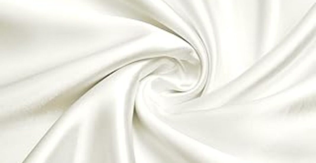 Close-up of smooth, white satin fabric twisted into a gentle spiral pattern.