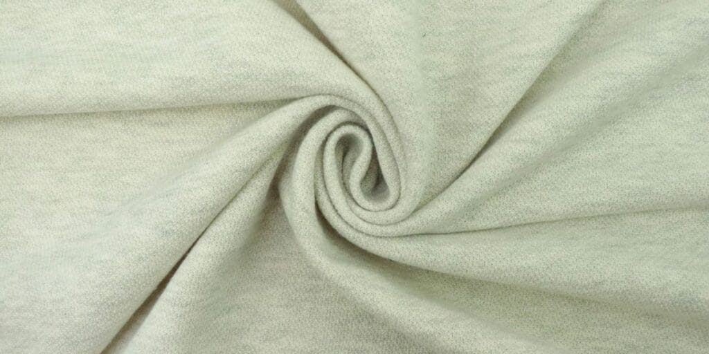 Light grey heathered knit fabric twisted into a spiral.