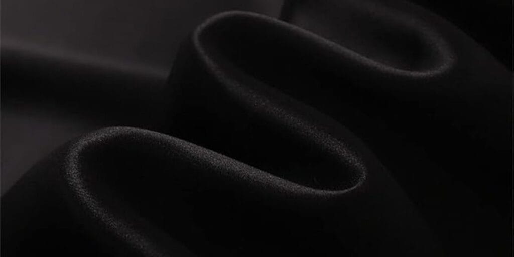 Close-up of black satin fabric with smooth, wavy folds.