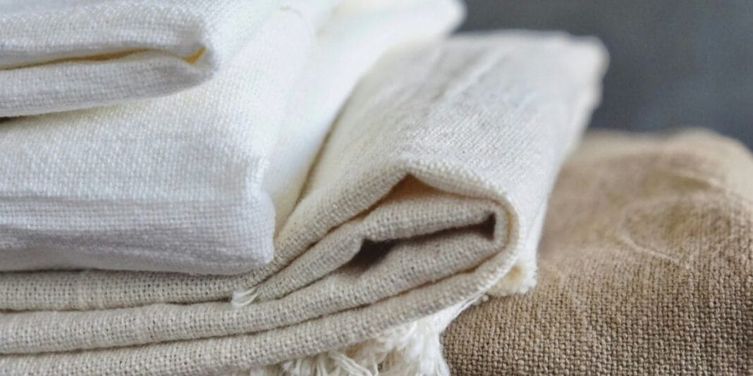 Stack of folded natural linen fabrics in neutral tones