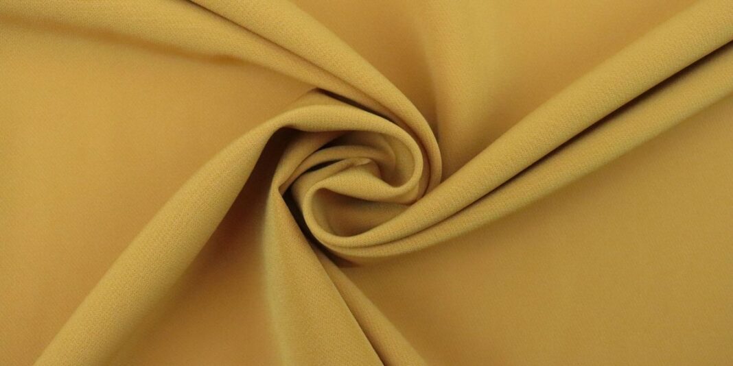 Close-up of mustard yellow fabric twisted into a swirl pattern.