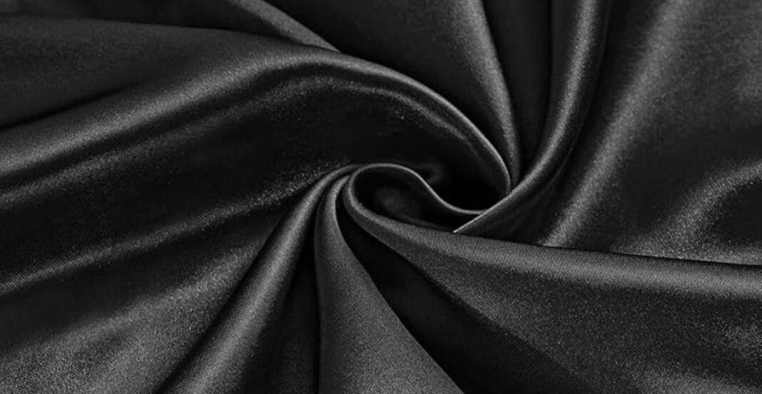 Close-up of black satin fabric with smooth, shiny texture arranged in soft folds.
