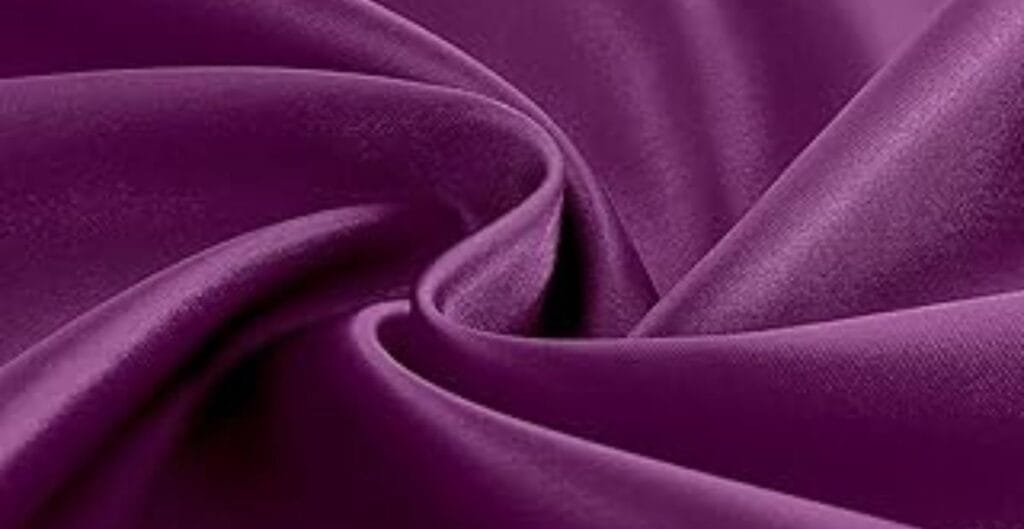 Close-up of smooth, shiny purple satin fabric with elegant folds.
