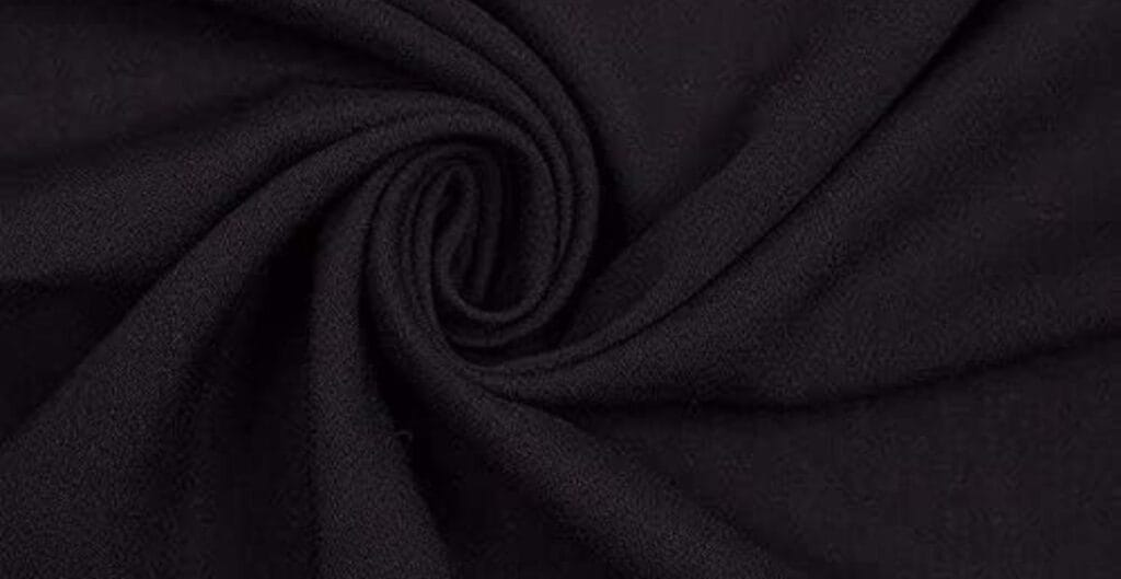Close-up of black fabric with a soft, slightly textured surface, twisted into a spiral pattern.