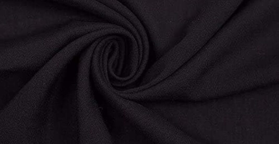 Close-up of black fabric with a soft, slightly textured surface, twisted into a spiral pattern.