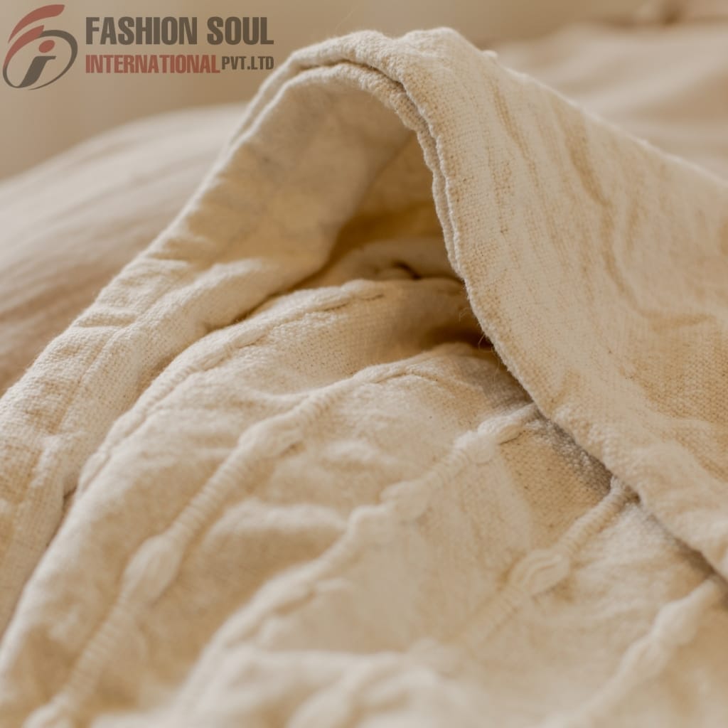 Close-up of beige, textured fabric with visible stitching and folds, showing a soft, woven material.