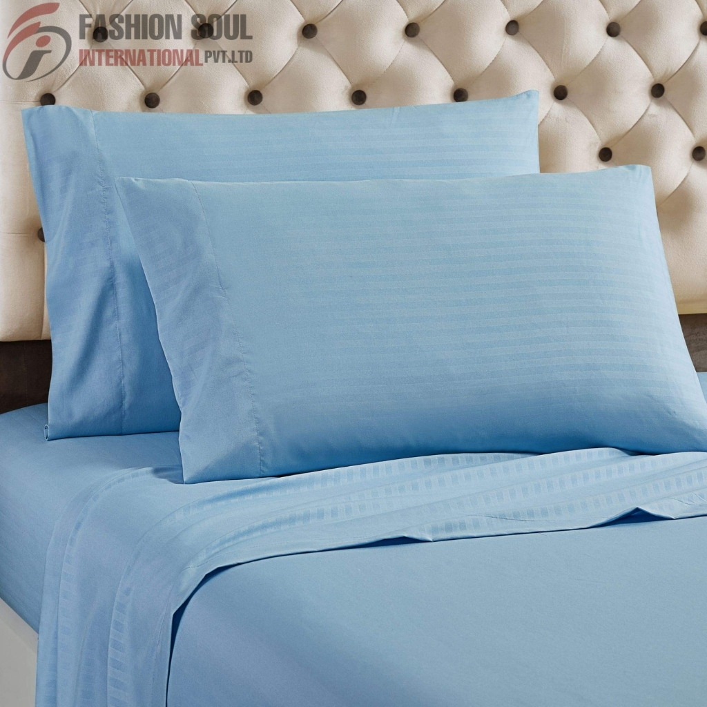 Light blue bed sheets and pillowcases on a bed with a tufted beige headboard, creating a calm and elegant bedroom atmosphere.
