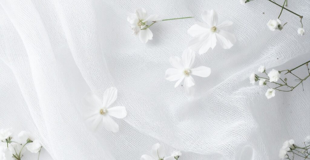 White fabric with scattered white flowers and small white buds.