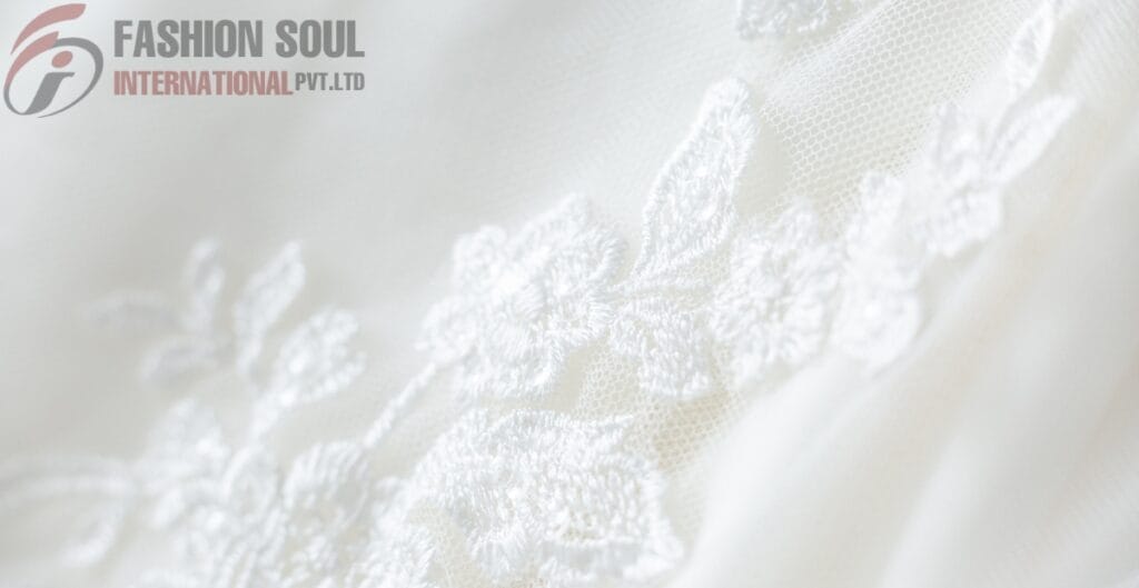 Close-up of delicate white linen fabric with floral embroidery by Fashion Soul International Pvt. Ltd.