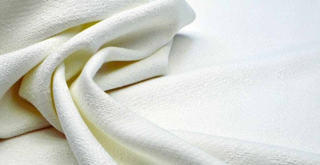 Close-up image of soft, white fabric with a textured surface, gently folded.