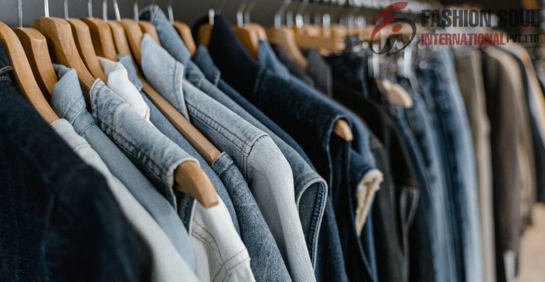 A row of denim and casual jackets hanging on wooden hangers on a clothing rack in a store.