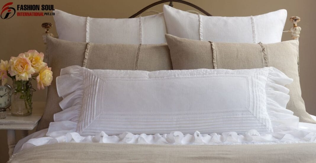 Folded chambray linen duvet covers in various neutral shades stacked neatly on a wooden bench