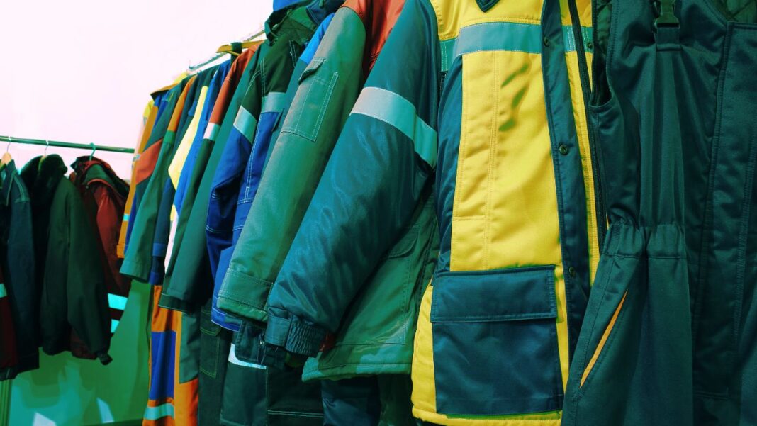 Colorful collection of different types of workwear jackets hanging on a rack.