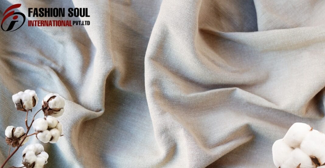 A close-up of elegant beige textile fabric with cotton flowers placed on the side, featuring a logo of 
