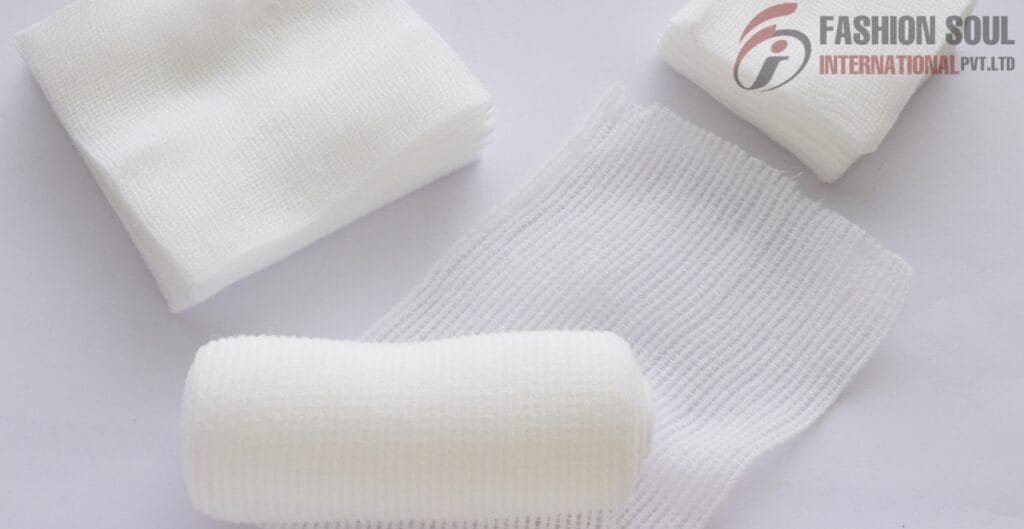 A collection of white medical gauze and bandage rolls, some stacked and others laid out flat on a white surface.