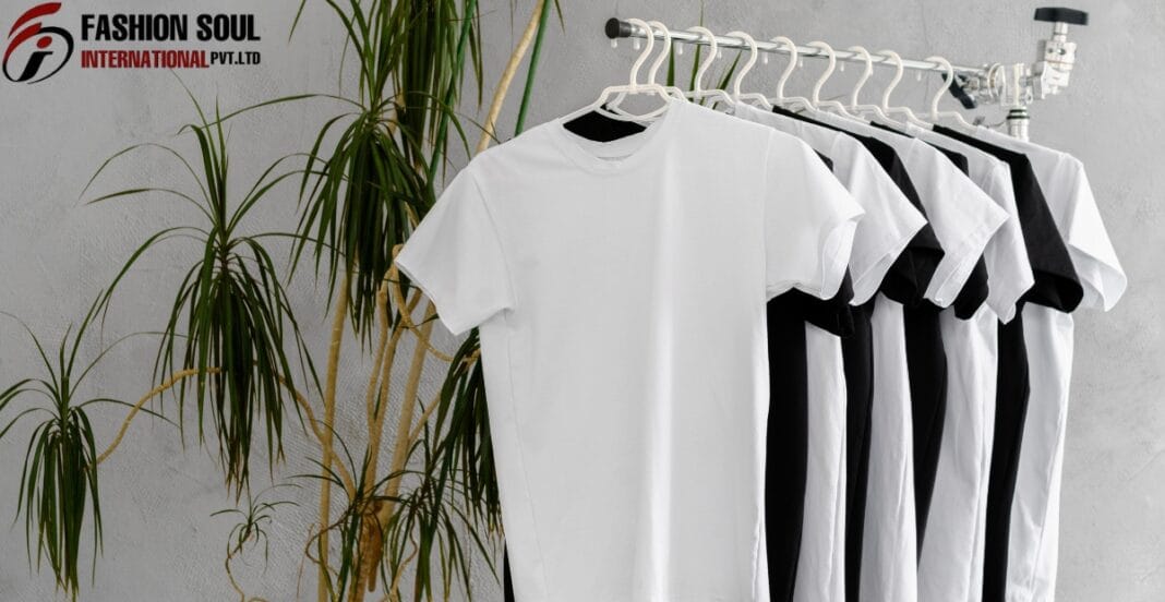 A row of white and black T-shirts hanging on a white clothing rack, with a green plant and a gray wall in the background. The top left corner features the logo 