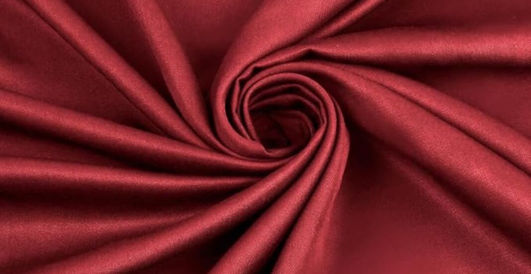 Close-up of red satin fabric arranged in a spiral pattern.