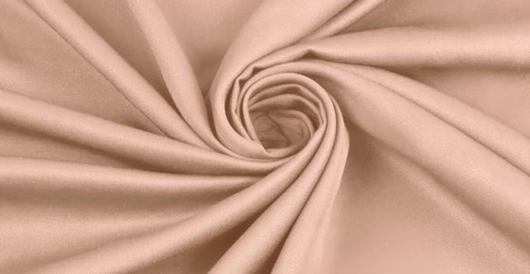 Close-up of light brown fabric with a smooth texture, gathered in a spiral pattern.