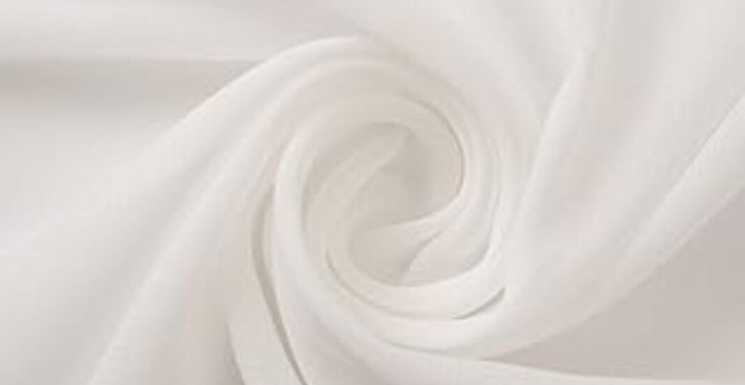 Close-up of white satin fabric softly swirled into a spiral pattern, showcasing its smooth and glossy texture.