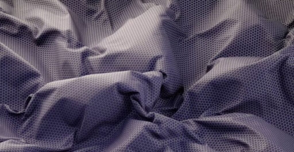 Wrinkled purple fabric with a hexagonal mesh overlay pattern.