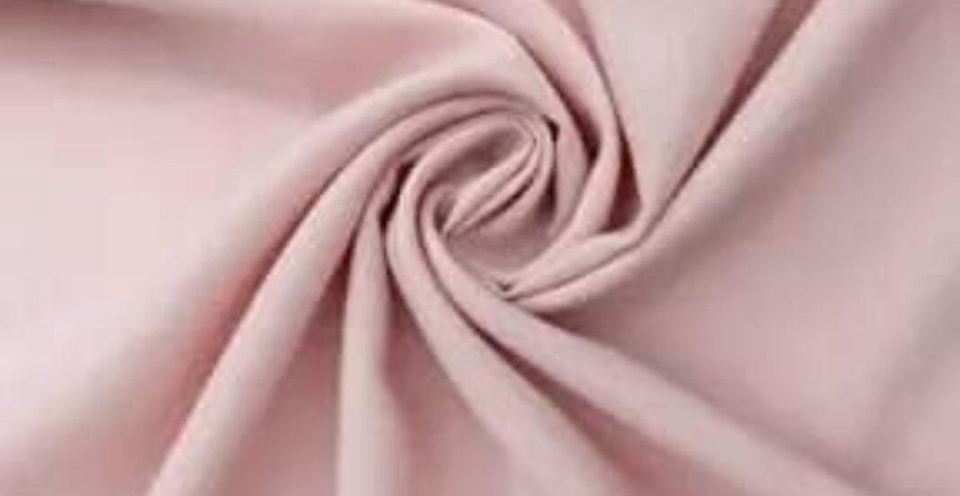 Light pink fabric twisted into a swirl pattern, showcasing its smooth texture and soft drape.
