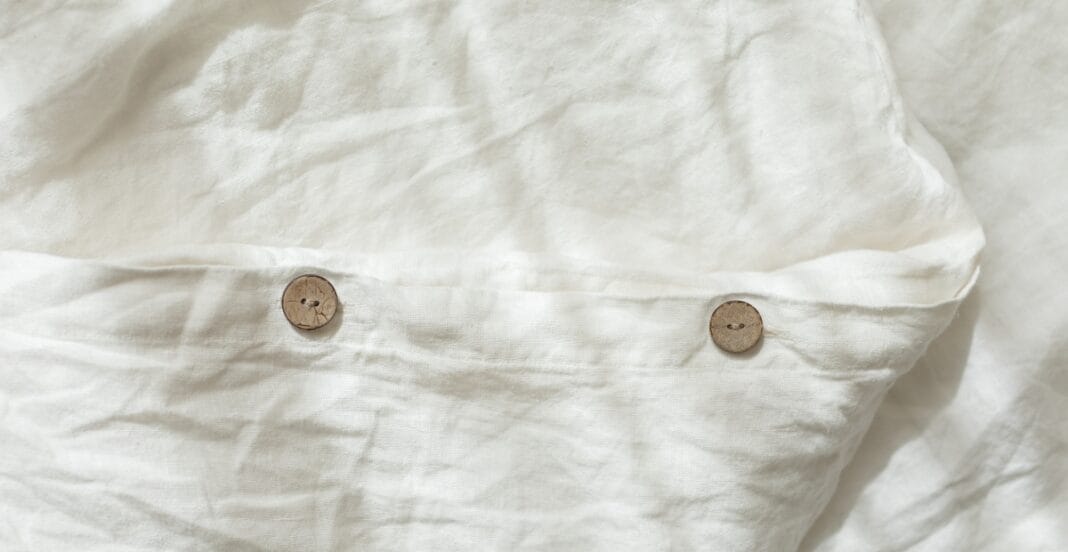 A close-up of a white fabric shirt with two small wooden buttons sewn onto it.