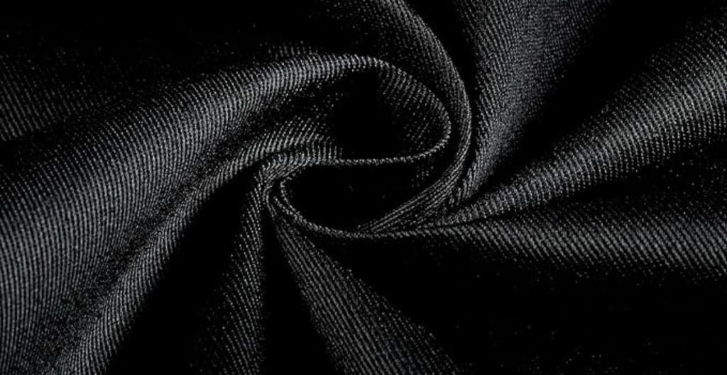 Close-up of black satin fabric twisted into a swirl, showing its smooth texture and subtle sheen.